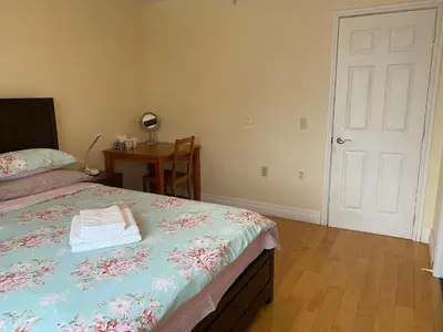 a bedroom with a bed and a table with a chair at Dairy Homestay in Toronto
