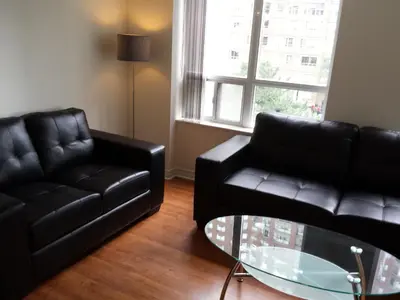 a living room with two black leather couches and a glass table at 2 Bedroom 1 Bathroom Prime Location in Mississauga in Mississauga