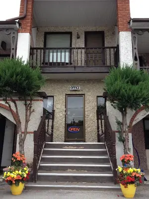 a building with stairs in front of a door with flowers at Cedar Springs Motel in Acton