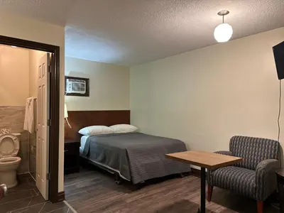 a bedroom with a bed and a table and a chair at Cedar Springs Motel in Acton