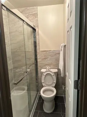 a bathroom with a toilet and a glass shower at Cedar Springs Motel in Acton