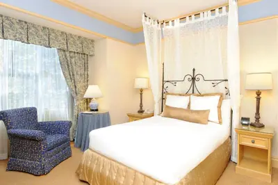 a bedroom with a bed and a blue chair at Old Mill Toronto Hotel in Toronto