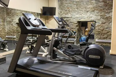 a gym with cardio machines in a room with a stone wall at Old Mill Toronto Hotel in Toronto