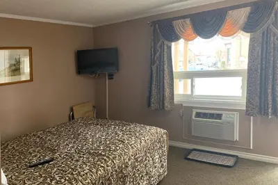 a bedroom with a bed and a television and a window at Lucien Motel in Whitby