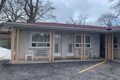 a house with a porch with two chairs on it at Lucien Motel in Whitby
