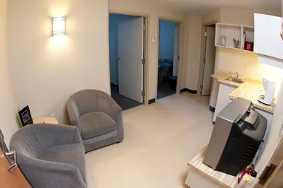 a living room with two chairs and a television at Residence & Conference Centre - Oshawa in Oshawa
