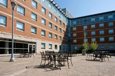 a courtyard with tables and chairs in front of a building at Residence & Conference Centre - Oshawa in Oshawa