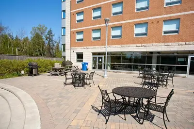 a group of tables and chairs in front of a building at Residence & Conference Centre - Oshawa in Oshawa
