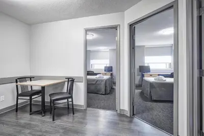 a room with a table and a bedroom with two beds at Residence & Conference Centre - King City in King City
