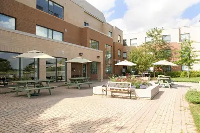 a courtyard with picnic tables and umbrellas in front of a building at Residence & Conference Centre - King City in King City