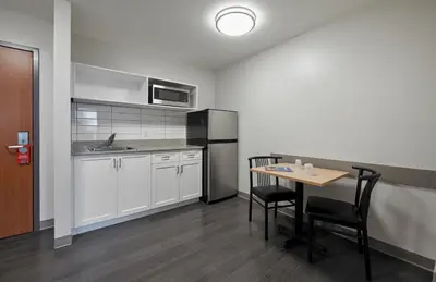 a kitchen with a table and chairs and a refrigerator at Residence & Conference Centre - King City in King City