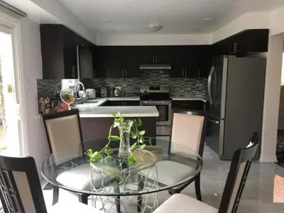 a kitchen with a glass table with chairs and a kitchen with a refrigerator at Home Base in Markham