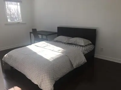 a bedroom with a bed with a table and a window at Home Base in Markham