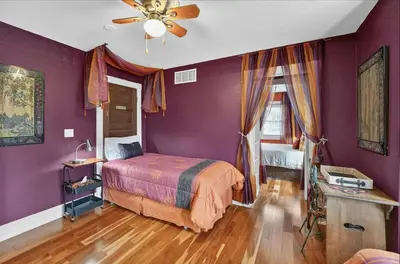 a bedroom with purple walls and a bed and a fan at Globetrotters B&B in Niagara on the Lake