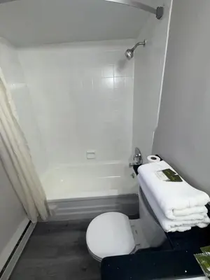 a white bathroom with a toilet and a towel at Advance Inn in Niagara Falls