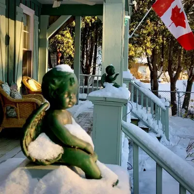 a statue of a little girl sitting on a porch in the snow at WeatherPine Inn in Niagara on the Lake
