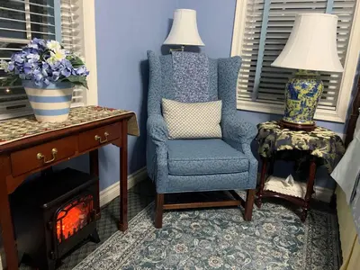 a blue room with a chair and a table with a lamp at WeatherPine Inn in Niagara on the Lake