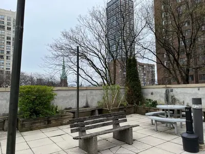 two benches and a table on a patio in a city at Neill Wycik Hostel in Toronto