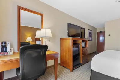 a hotel room with a desk with a bed and a television at Sandman Hotel & Suites London Downtown in London