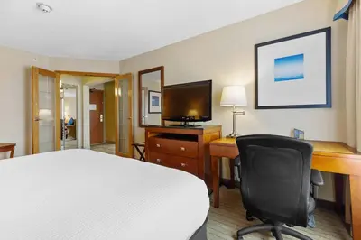 a hotel room with a bed and a desk and a television at Sandman Hotel & Suites London Downtown in London