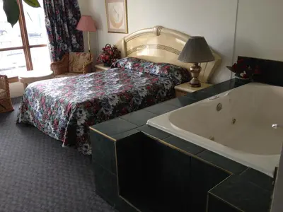 a bathroom with a tub and a bed and a bed and a bed at Rainbow Motor Inn - Fallsview in Niagara Falls