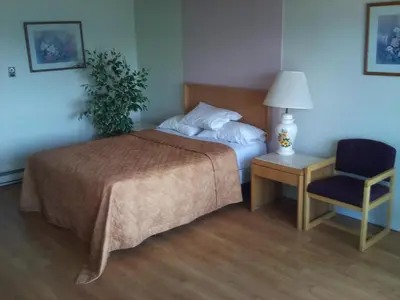 a bedroom with a bed and a chair and a lamp at Rainbow Motor Inn - Fallsview in Niagara Falls