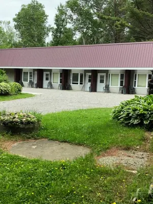 a building with a red roof and a grass yard at Noble Motel in Norland