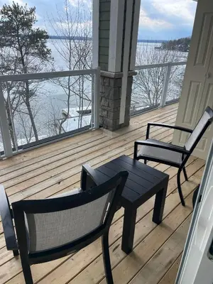 two chairs and a table on a porch with a view of the water at Touchstone Resort in Bracebridge
