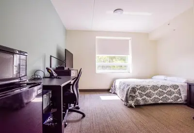 a bedroom with a bed and a desk and a television at United College in Waterloo