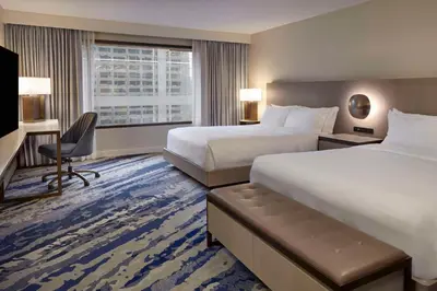 a hotel room with two beds and a desk at Hilton Toronto in Toronto