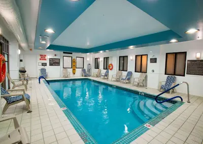 a pool in a hotel with blue water and chairs at Hampton Inn Toronto-Mississauga West in Mississauga