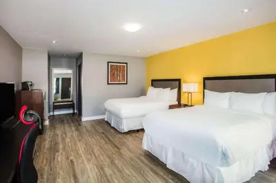 a hotel room with two beds and a yellow wall at Ramada by Wyndham Jackson's Point in Georgina