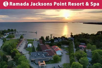 an aerial view of a town on the water with the sunset at Ramada by Wyndham Jackson's Point in Georgina