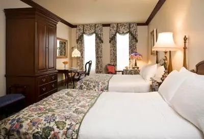 a hotel room with two beds and a desk at Prince of Wales in Niagara on the Lake
