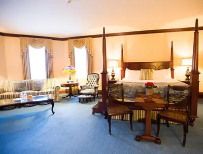 a bedroom with a bed and a couch and a table at Prince of Wales in Niagara on the Lake