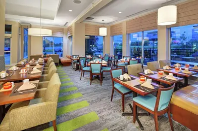a restaurant with tables and chairs and windows at Hilton Garden Inn Toronto-Oakville in Oakville