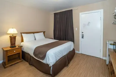 a hotel room with a large bed and a window at Maples Motel in Orillia