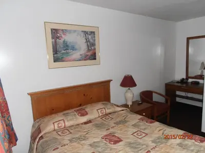 a bedroom with a bed and a desk with a lamp at Maples Motel in Orillia