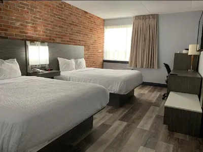 a hotel room with two beds and a brick wall at Travelodge by Wyndham Barrie in Barrie