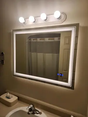 a bathroom mirror with a sink and lights above it at Howard Johnson by Wyndham Lindsay in Lindsay