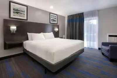 a hotel room with a bed and a blue chair at Days Inn by Wyndham Barrie in Barrie