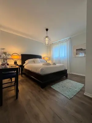a bedroom with a bed and a table and a chandelier at Lulu's Bed & Breakfast in Niagara on the Lake
