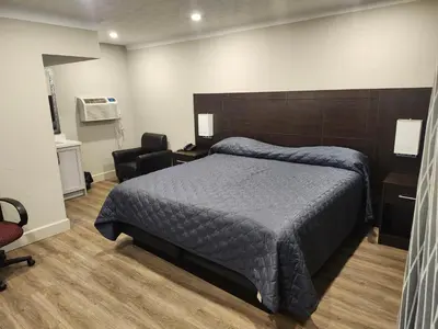 a bedroom with a bed and a chair at Fairway Inn & Suites in Kitchener