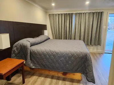 a bedroom with a bed and a table and a window at Fairway Inn & Suites in Kitchener