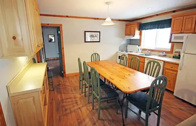 a kitchen with a wooden dining table and chairs at Elmhirst's Resort in Keene