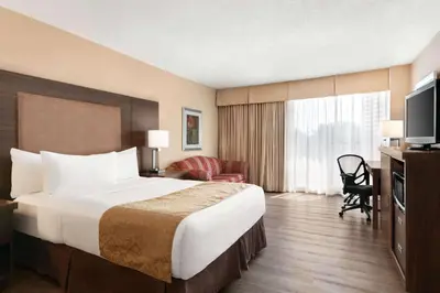a hotel room with a large bed and a television at Ramada by Wyndham Belleville Harbourview Conference Center in Belleville