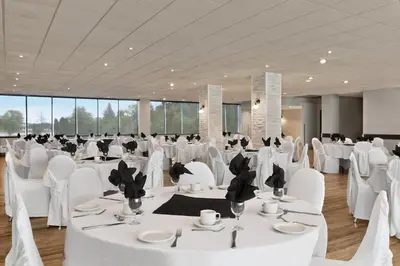 a banquet hall with white tables and white chairs at Ramada by Wyndham Belleville Harbourview Conference Center in Belleville