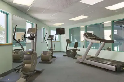a gym with cardio equipment in a room with windows at Ramada by Wyndham Belleville Harbourview Conference Center in Belleville