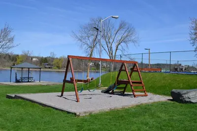 a playground in a park next to a body of water at Motel 6 Campbellford, ON in Campbellford