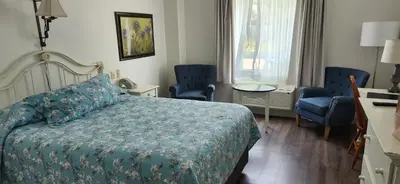 a bedroom with a bed and two blue chairs at The Village Inn of Lakefield in Lakefield